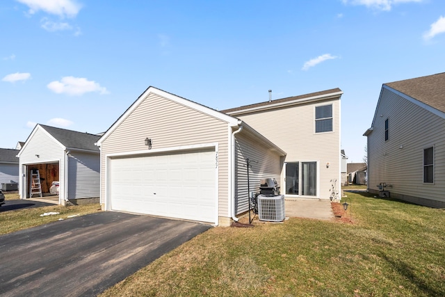 rear view of property with cooling unit, a yard, and a garage