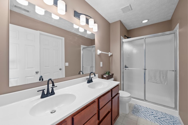 bathroom featuring tile patterned flooring, vanity, an enclosed shower, toilet, and a textured ceiling