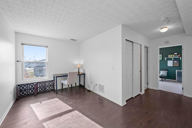 empty room with dark hardwood / wood-style floors and a textured ceiling