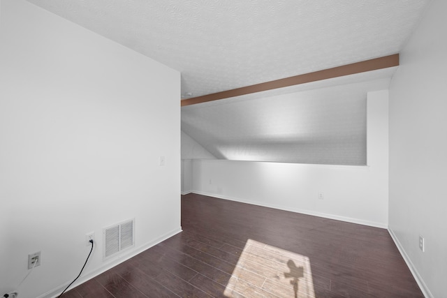 bonus room with dark wood-type flooring, a textured ceiling, and vaulted ceiling