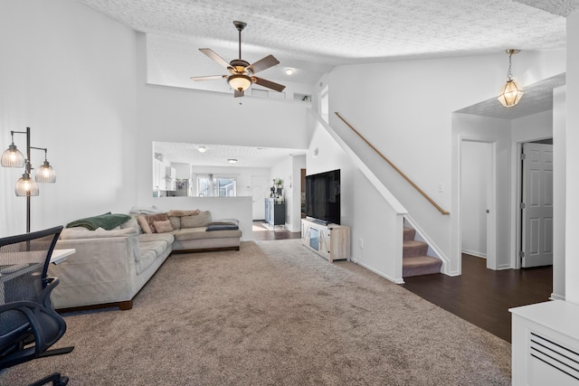 living room featuring dark colored carpet, ceiling fan, high vaulted ceiling, and a textured ceiling