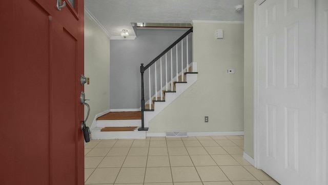 entrance foyer featuring light tile patterned floors and ornamental molding