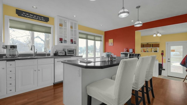 kitchen with white cabinetry, a kitchen breakfast bar, sink, and white dishwasher