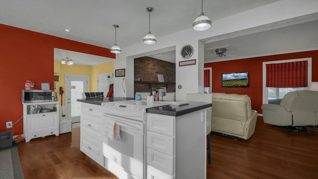 kitchen with white electric stove, a breakfast bar area, white cabinets, hanging light fixtures, and dark wood-type flooring