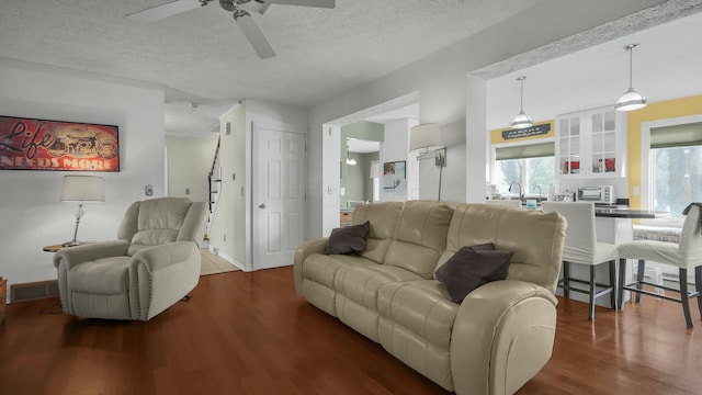 living room featuring ceiling fan, dark hardwood / wood-style floors, and a textured ceiling