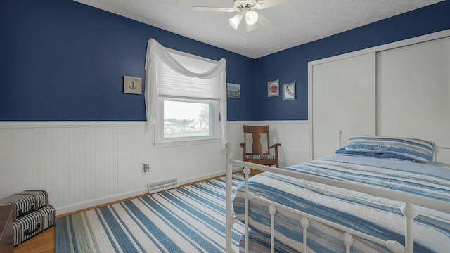 bedroom with hardwood / wood-style flooring, ceiling fan, a textured ceiling, and a closet