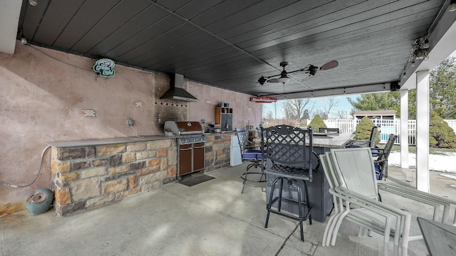 view of patio with a bar, ceiling fan, grilling area, and exterior kitchen