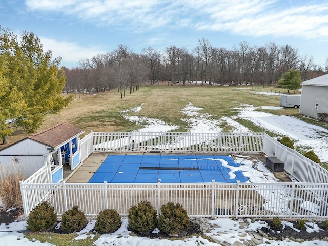 snow covered pool featuring a storage shed, a yard, and a patio