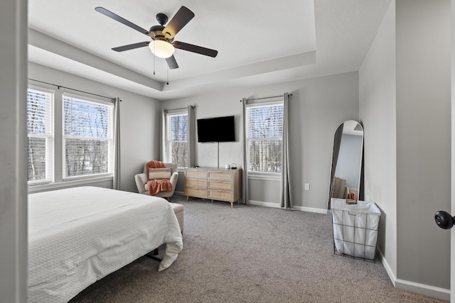 carpeted bedroom featuring ceiling fan and a tray ceiling