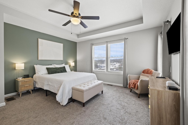 bedroom with carpet flooring, ceiling fan, and a tray ceiling