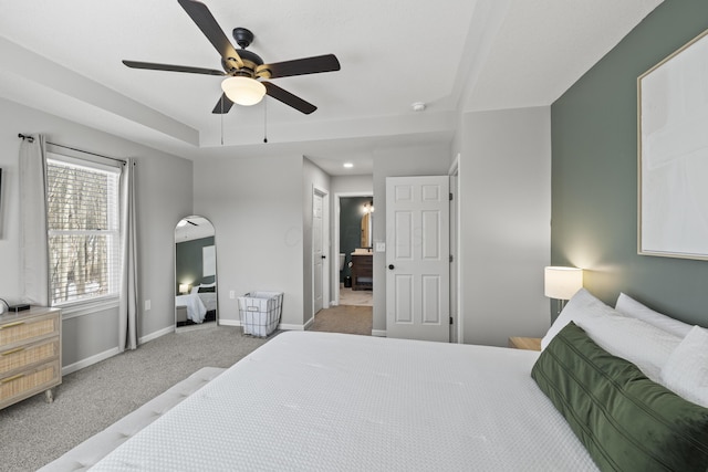 carpeted bedroom featuring ceiling fan and a tray ceiling