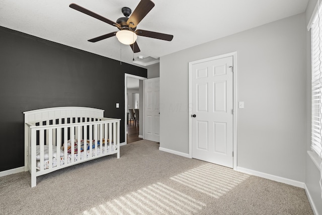 unfurnished bedroom featuring a crib, ceiling fan, and carpet