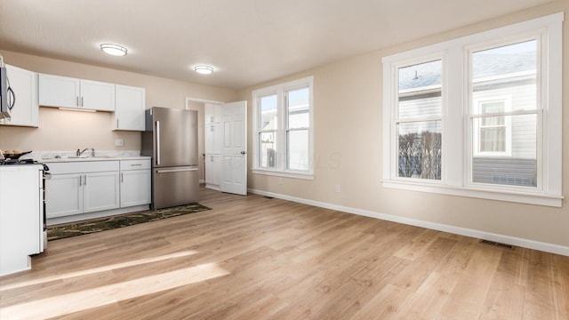 kitchen featuring sink, light hardwood / wood-style flooring, stainless steel appliances, and white cabinets