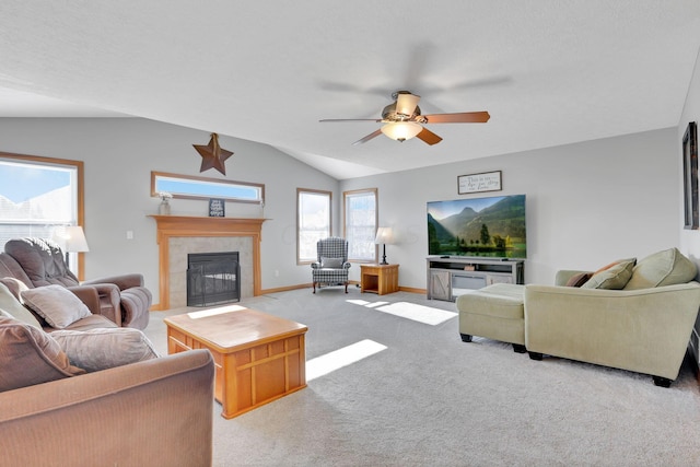 carpeted living room with ceiling fan, vaulted ceiling, and a tile fireplace