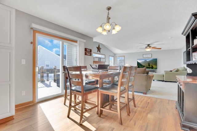 dining area with vaulted ceiling, ceiling fan with notable chandelier, and light wood-type flooring