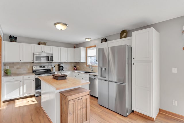 kitchen with tasteful backsplash, white cabinetry, a center island, light hardwood / wood-style floors, and stainless steel appliances