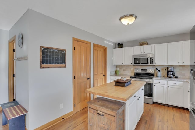 kitchen featuring appliances with stainless steel finishes, light wood-type flooring, a kitchen island, and white cabinets