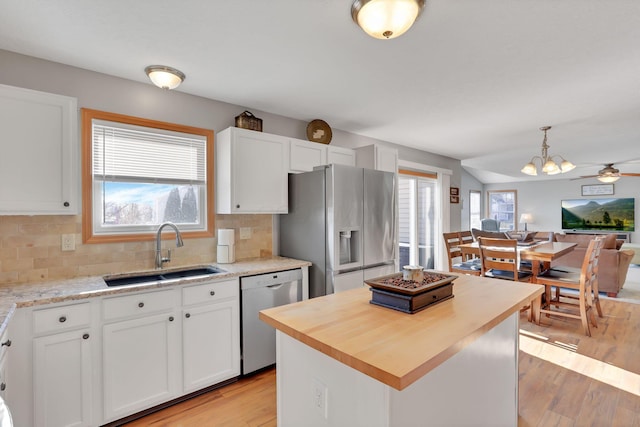 kitchen with pendant lighting, sink, white cabinetry, stainless steel appliances, and a center island