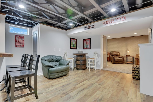 sitting room with hardwood / wood-style flooring and brick wall