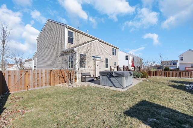 back of house with a hot tub, a patio area, and a lawn