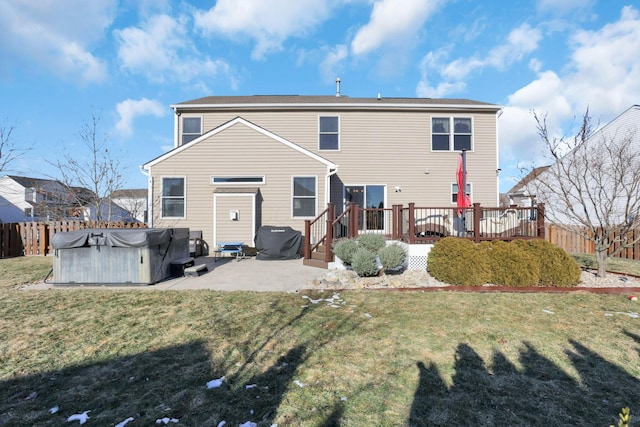 rear view of house featuring a wooden deck, a yard, a hot tub, and a patio