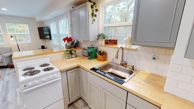 kitchen with sink, gray cabinetry, backsplash, and electric stove