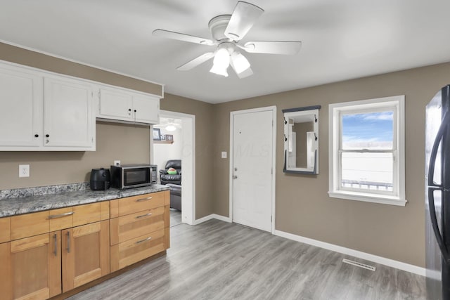 kitchen with white cabinetry, black refrigerator, ceiling fan, and light hardwood / wood-style flooring