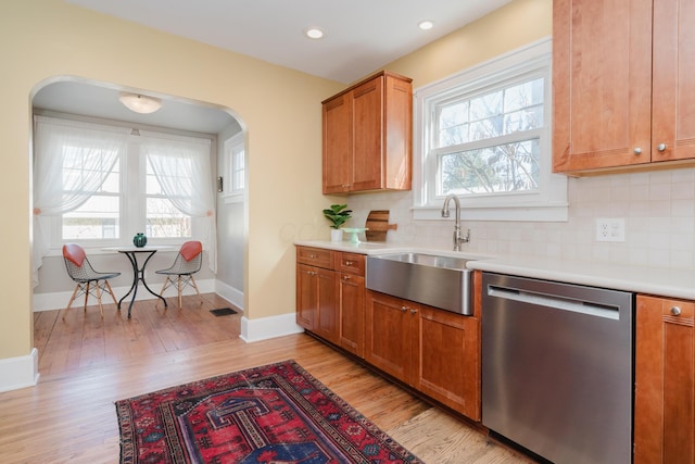 kitchen featuring tasteful backsplash, sink, stainless steel dishwasher, and light hardwood / wood-style floors