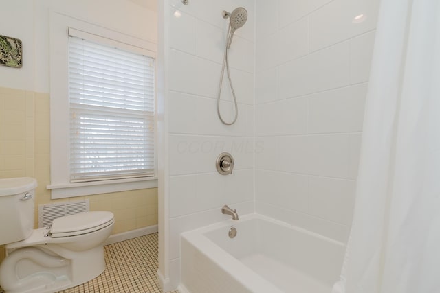 bathroom featuring tile walls, toilet, a healthy amount of sunlight, shower / bathtub combination with curtain, and tile patterned floors