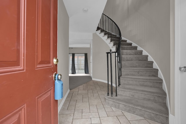 foyer entrance with stone finish floor, baseboards, and stairs