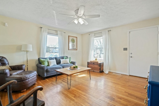 living room with a textured ceiling, ceiling fan, and light wood-type flooring