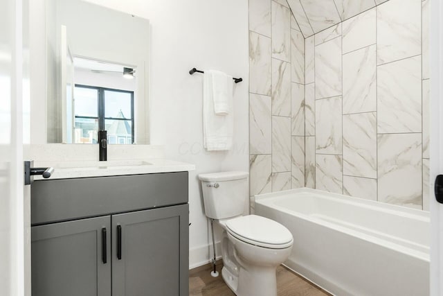 full bathroom featuring vanity, hardwood / wood-style flooring, tiled shower / bath combo, and toilet