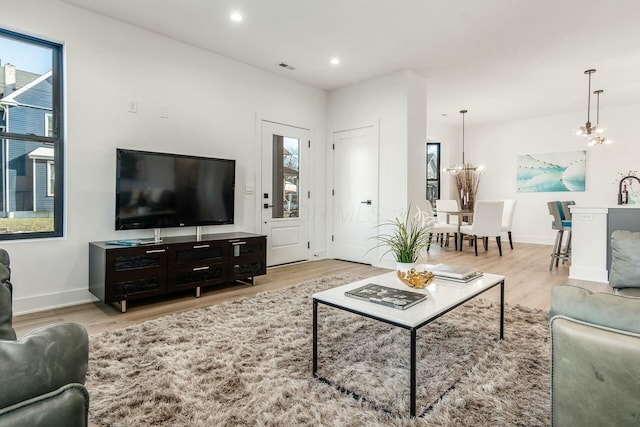 living room with a notable chandelier and light wood-type flooring