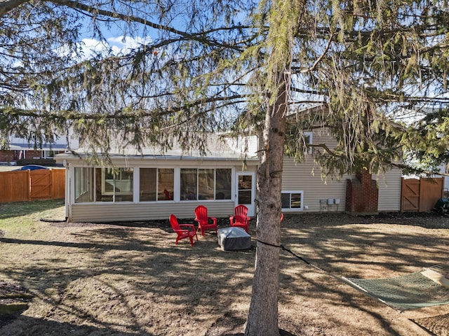 back of property featuring a sunroom, a gate, and fence