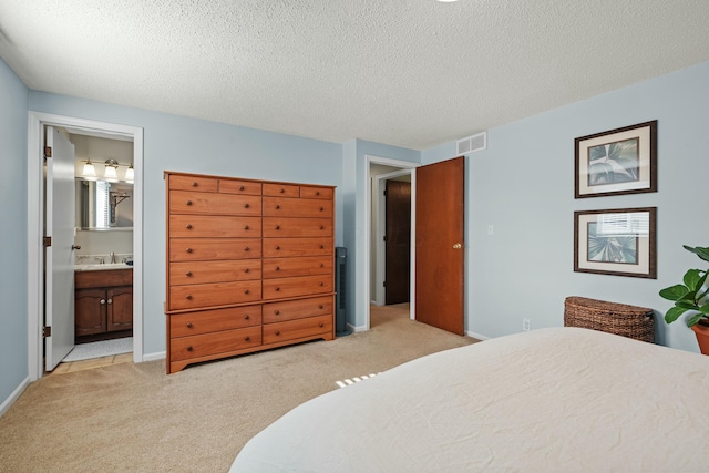 bedroom featuring visible vents, ensuite bathroom, a textured ceiling, and light colored carpet