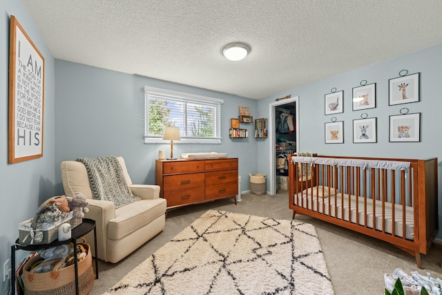 bedroom featuring a textured ceiling, a spacious closet, a closet, and light colored carpet