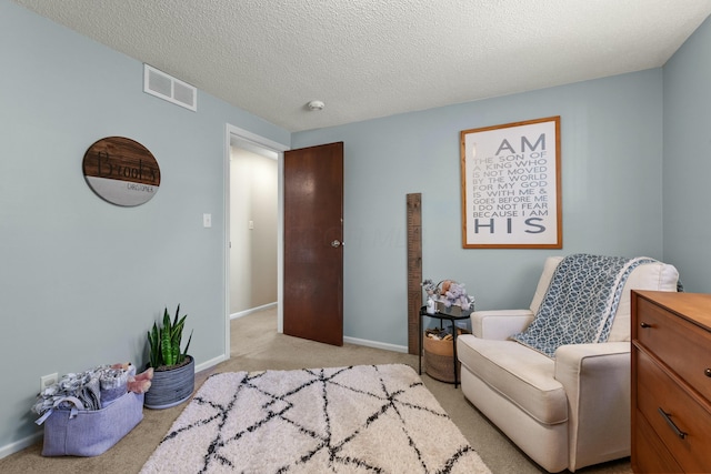 living area featuring baseboards, a textured ceiling, visible vents, and light colored carpet