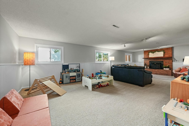 game room with carpet, visible vents, wainscoting, and a textured ceiling