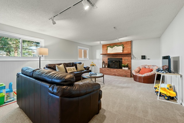 living room with visible vents, light colored carpet, a textured ceiling, and wainscoting