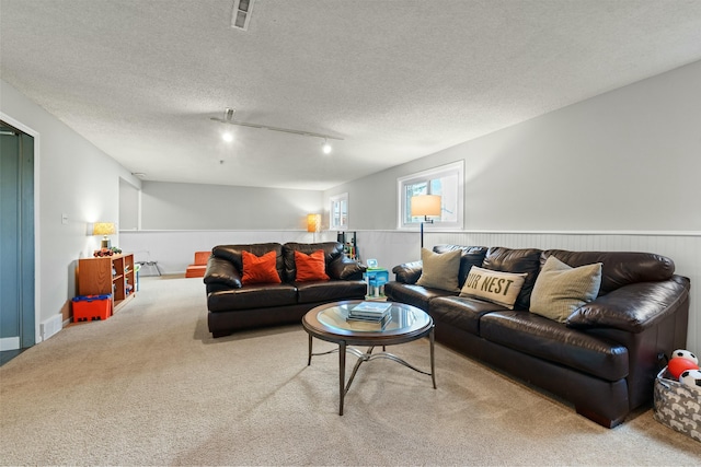 living area featuring carpet, visible vents, and a textured ceiling