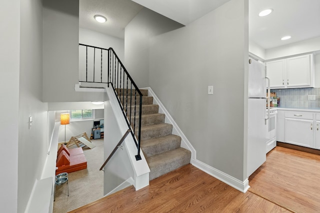 staircase with recessed lighting, baseboards, and wood finished floors