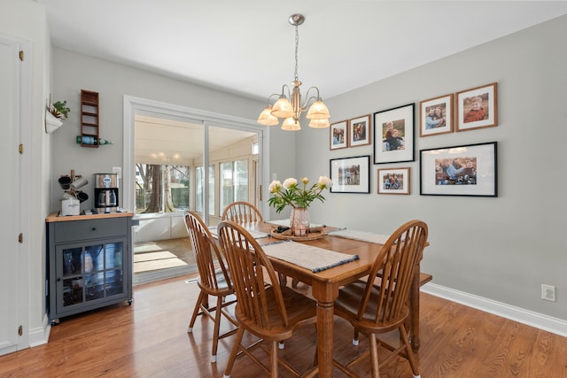 dining space featuring light wood-type flooring, baseboards, and a chandelier