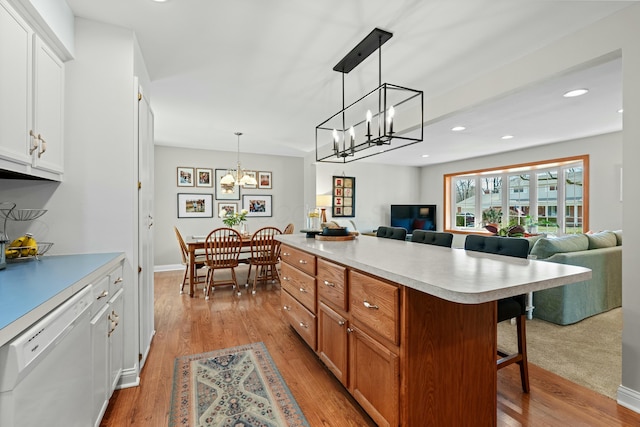 kitchen featuring a breakfast bar, white cabinetry, open floor plan, a center island, and dishwasher