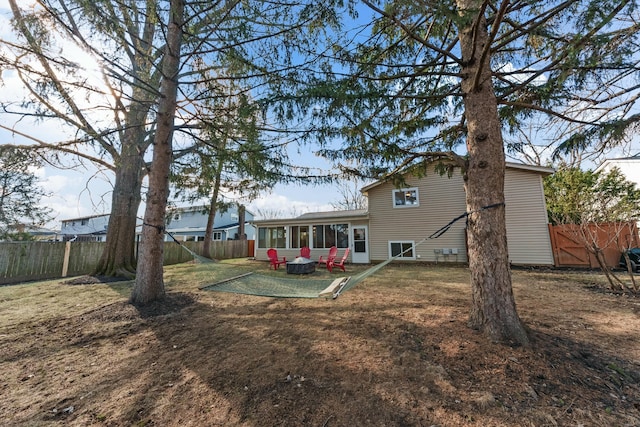 rear view of property featuring a yard, a fenced backyard, and a sunroom