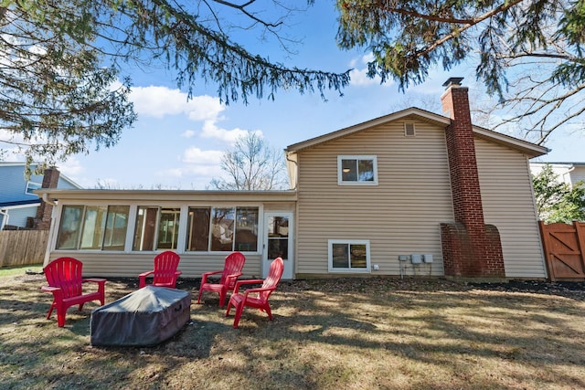 rear view of house with a lawn, a chimney, fence, and a sunroom