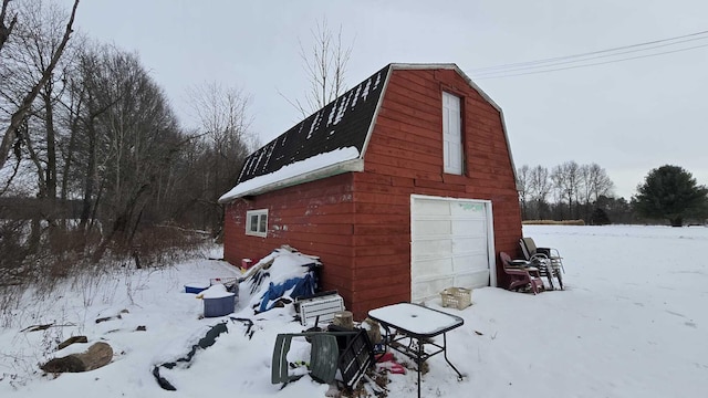 view of snowy exterior with an outbuilding and a garage