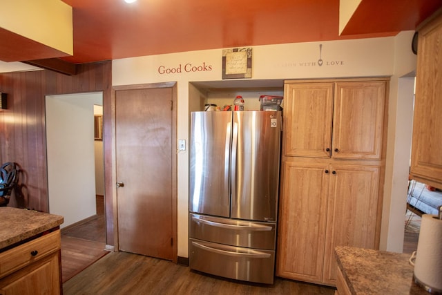 kitchen featuring dark hardwood / wood-style flooring, wooden walls, and stainless steel refrigerator