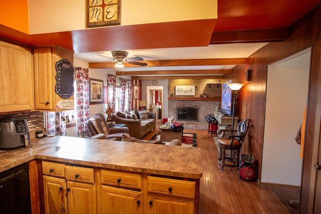 kitchen with beam ceiling, black dishwasher, a fireplace, hardwood / wood-style floors, and backsplash