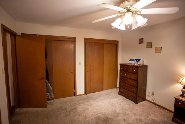 carpeted bedroom featuring ceiling fan and multiple closets