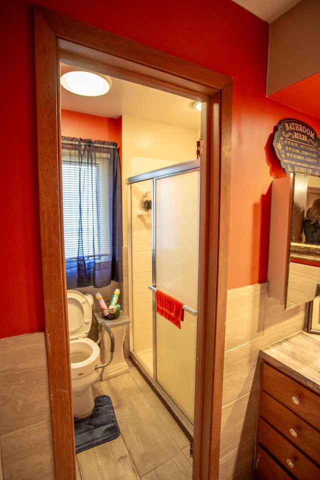 bathroom featuring a shower with shower door and toilet